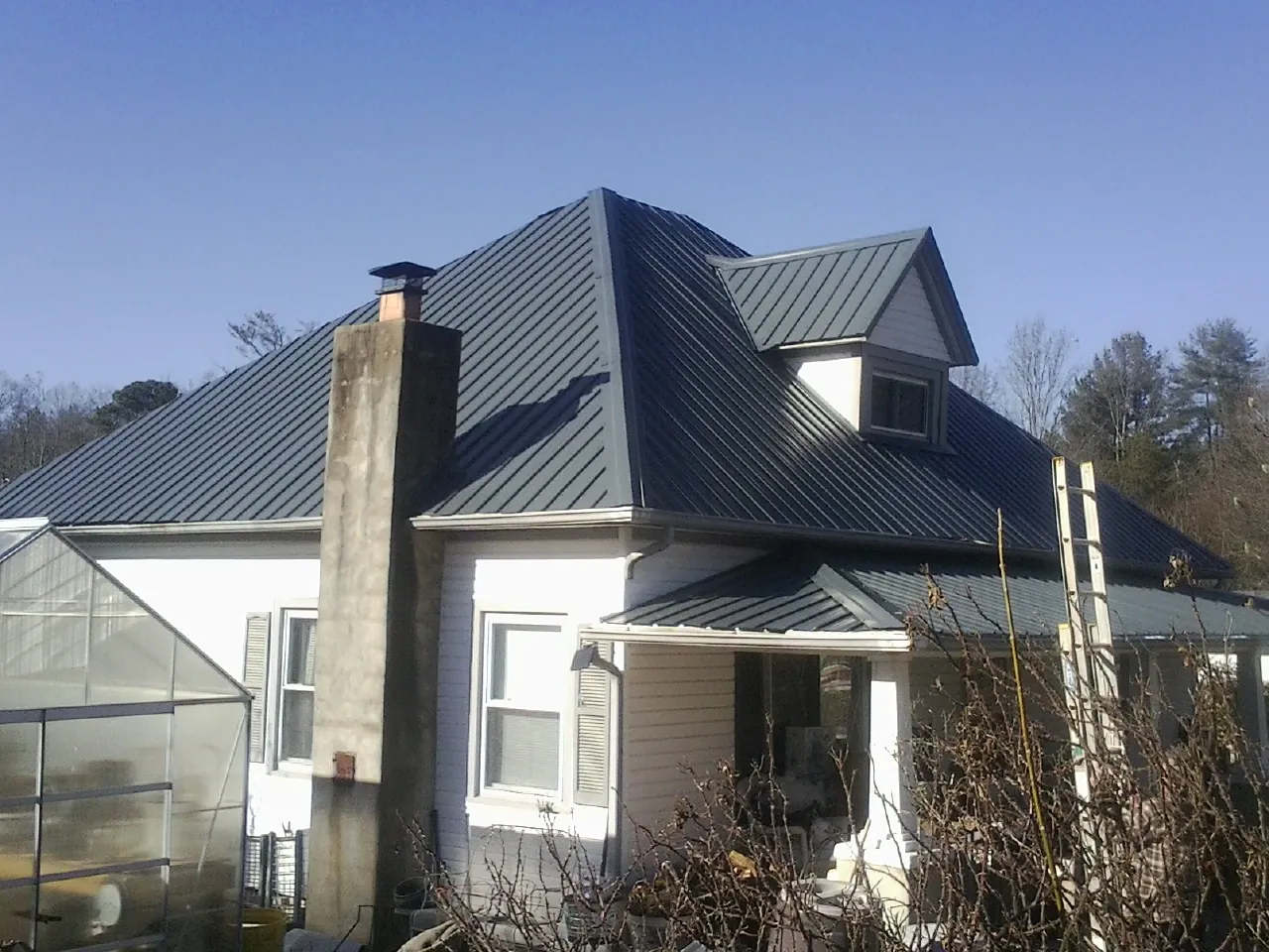 Dark blue standing seam metal roof on a white farmhouse with dormer — Slate & Tile Roof Repair by Roofing Brothers in Mexico