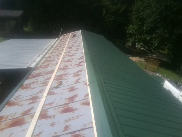 Old rusted panels beside newly installed green metal roofing — Wind Damage Roof Repair by Roofing Brothers in Mexico