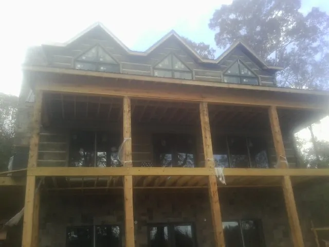 Dormers and porch framing on a large log home under construction — Roof Coating work by our crew in Mexico
