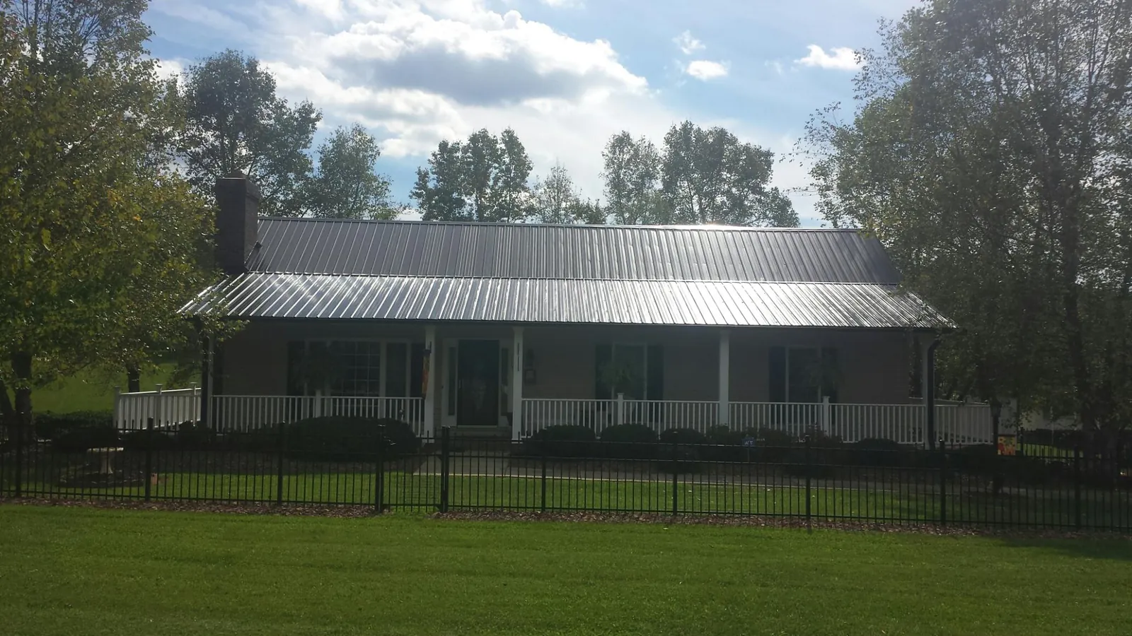 Gray metal roof on a brick ranch with a full width front porch — Gutter Guard Installation work by our crew in Mexico