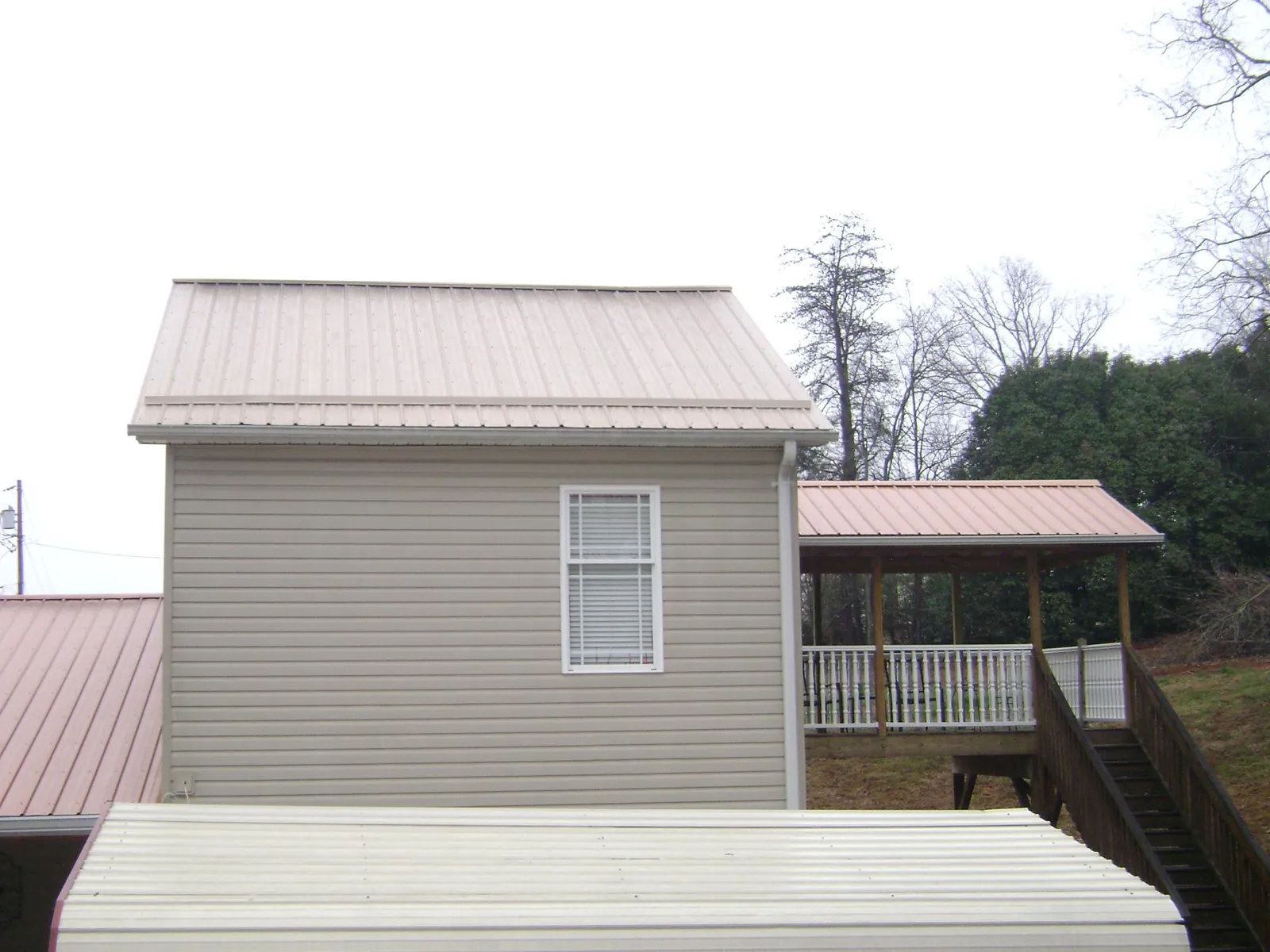 Tan metal roofs on a two story addition and attached porch, from a Roof Replacement job in Mexico